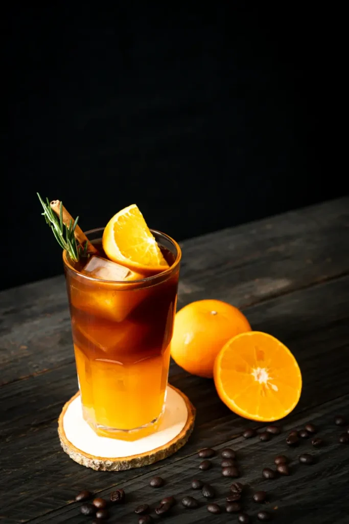 Americano cocktail lavet af campari og sød vermouth med appelsin og citron ved siden af.