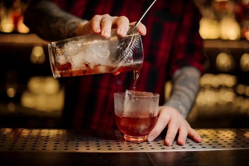 Bartender på en bar i byen mixer en Vieux Carrè cocktail drink.